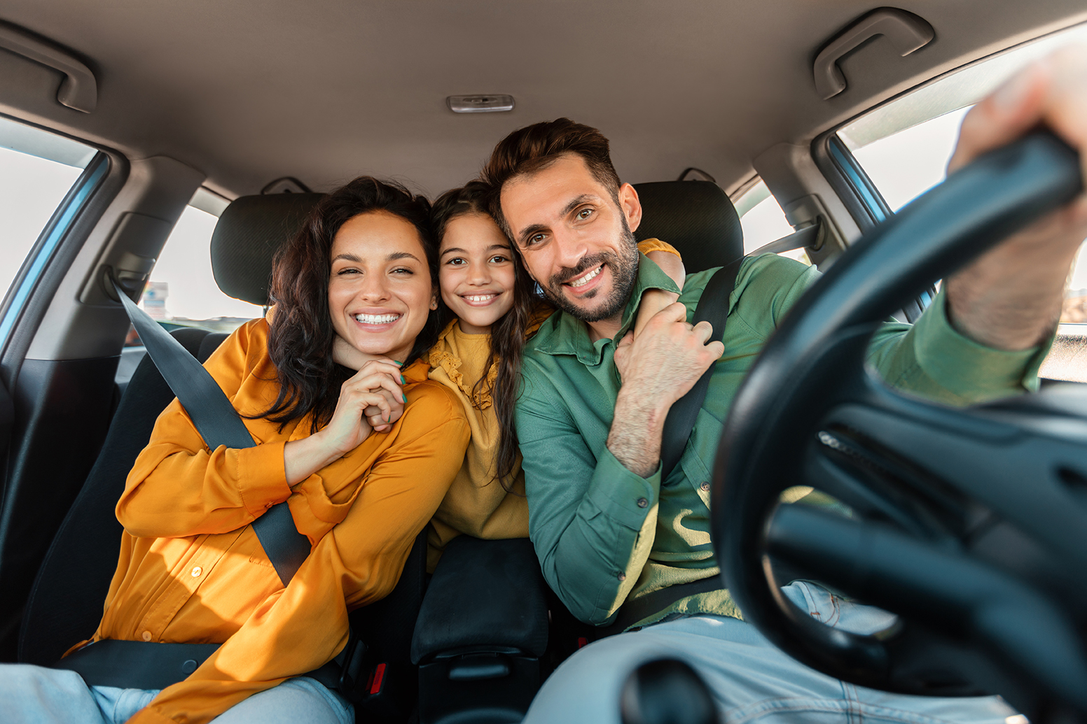 Automobile rent and purchase. Excited family embracing sitting in new car driving and enjoying road trip on vacation